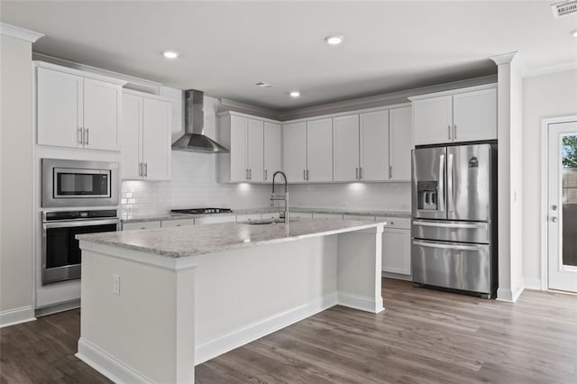 3382 Monarch Ave, Duluth, GA 30096 - kitchen featuring appliances with stainless steel finishes, wall chimney range hood, a center island with sink, tasteful backsplash, and dark wood finished floors