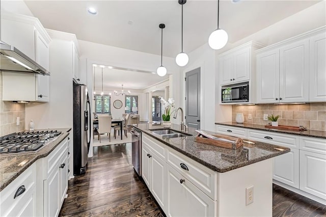 kitchen with wall chimney exhaust hood, decorative backsplash, appliances with stainless steel finishes, and an island with sink