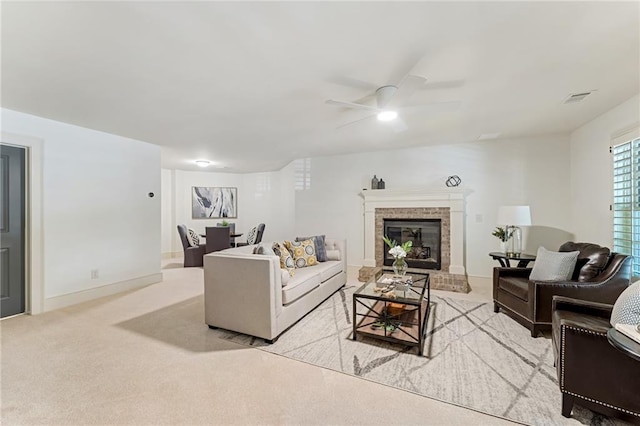 living room with ceiling fan, light colored carpet, and a fireplace