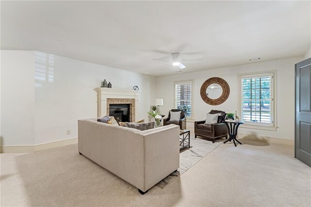 living room with ceiling fan, light colored carpet, and a brick fireplace