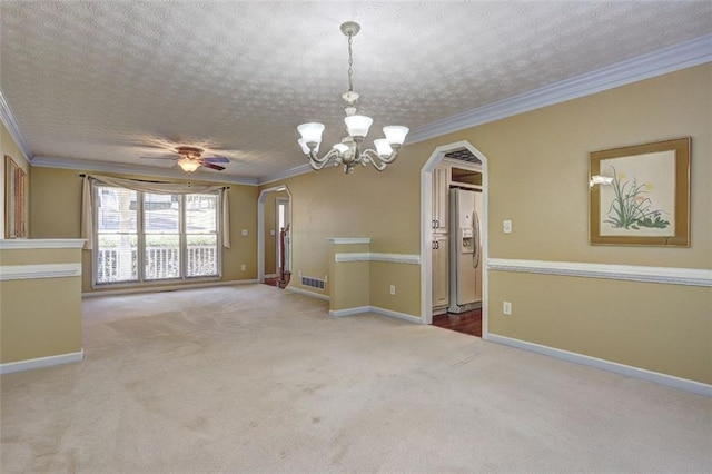 carpeted empty room featuring arched walkways, visible vents, ornamental molding, a textured ceiling, and baseboards