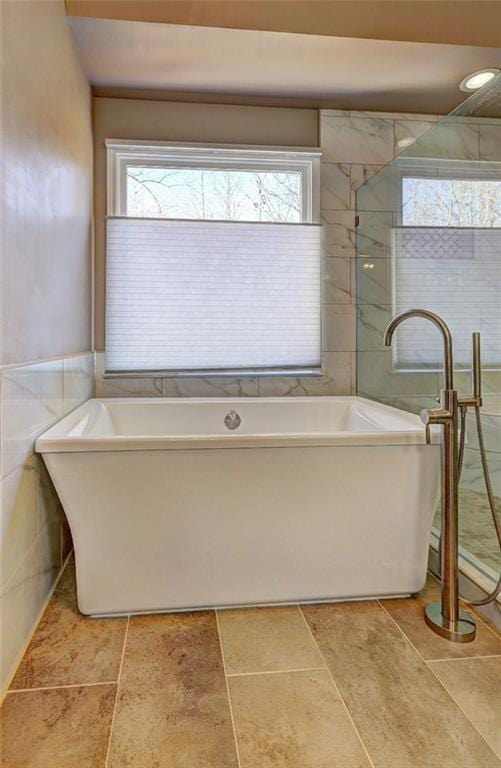 bathroom with tile walls and a freestanding bath