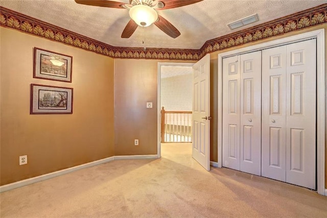 unfurnished bedroom with a textured ceiling, carpet flooring, visible vents, and baseboards