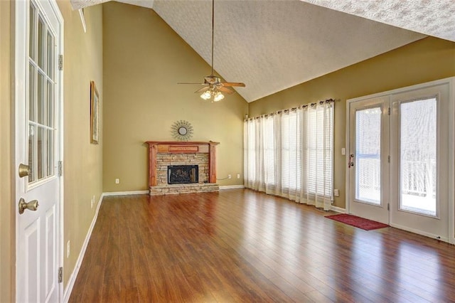 unfurnished living room featuring plenty of natural light, a stone fireplace, and wood finished floors