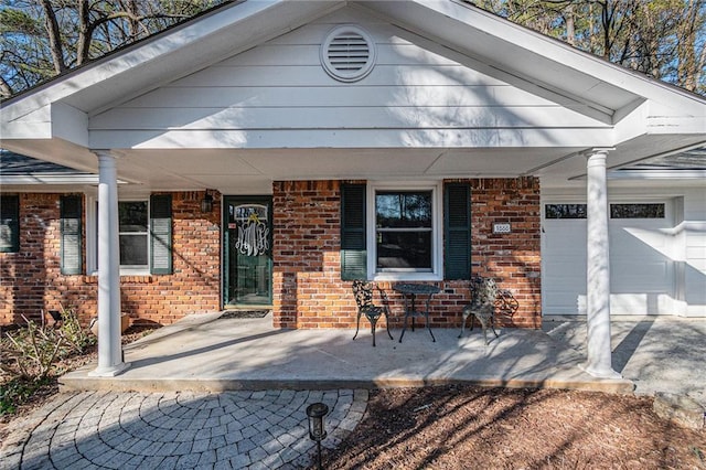 view of front of property featuring a porch, an attached garage, and brick siding