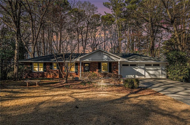 ranch-style home with an attached garage, brick siding, concrete driveway, and a front yard