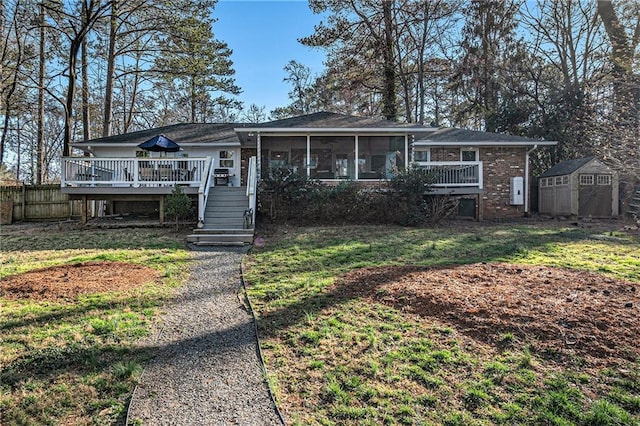 ranch-style house featuring an outdoor structure, a sunroom, stairs, a wooden deck, and a shed