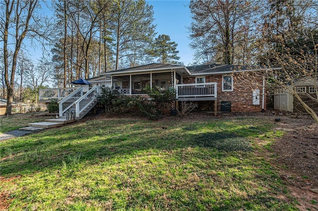 rear view of house with brick siding, a yard, a sunroom, a deck, and stairs