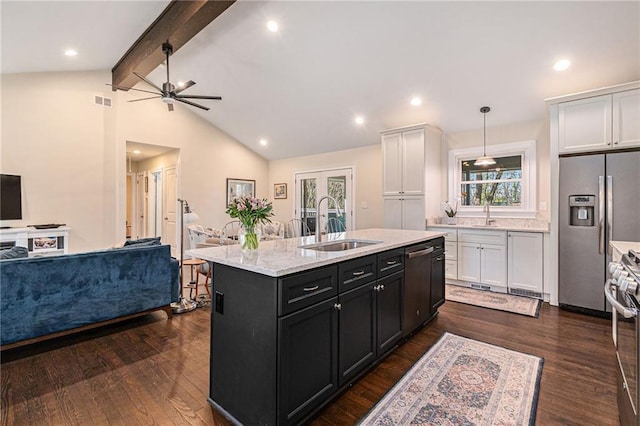 kitchen with open floor plan, stainless steel appliances, a sink, and white cabinets