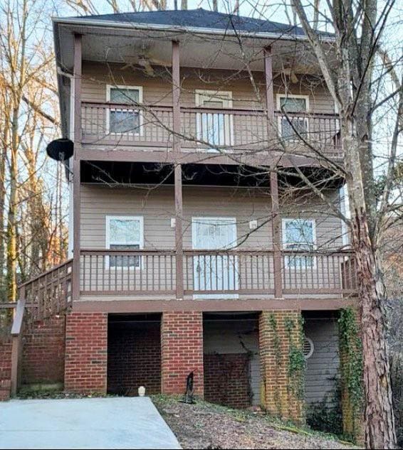 rear view of property with brick siding and a balcony