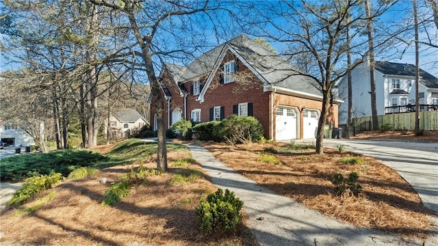 view of side of property featuring concrete driveway, a garage, fence, and brick siding