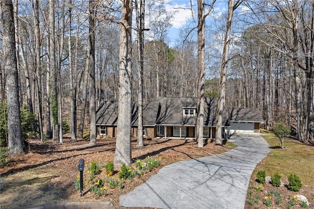 view of front of property featuring a wooded view and a detached garage