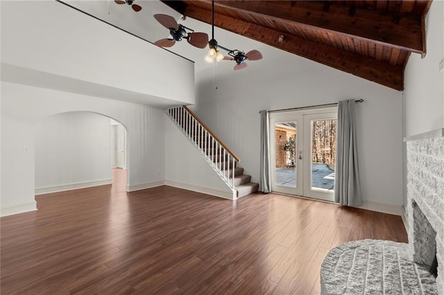 unfurnished living room featuring stairway, beamed ceiling, wood finished floors, and a ceiling fan