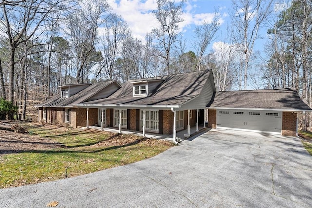 view of front of home with aphalt driveway, an attached garage, covered porch, and brick siding