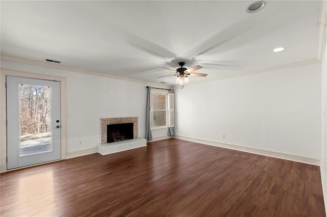 unfurnished living room with dark wood finished floors, a fireplace with raised hearth, visible vents, and ornamental molding