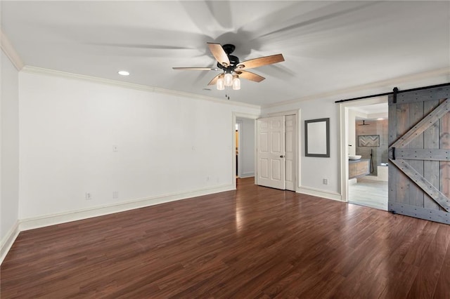 interior space with a barn door, baseboards, wood finished floors, and ornamental molding