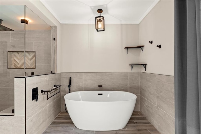 full bathroom featuring wood tiled floor, a freestanding tub, crown molding, and tiled shower