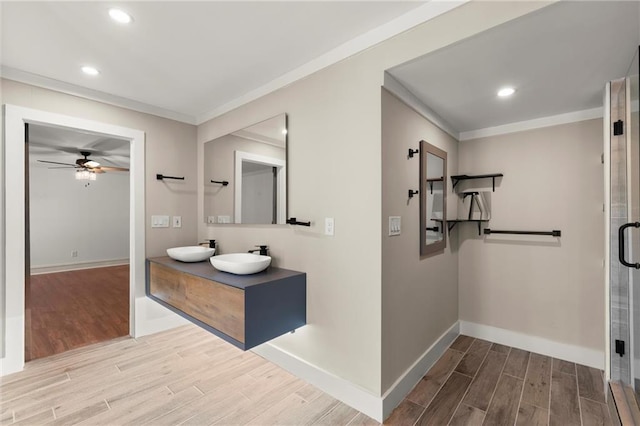 hallway featuring wood finished floors, baseboards, recessed lighting, a sink, and ornamental molding