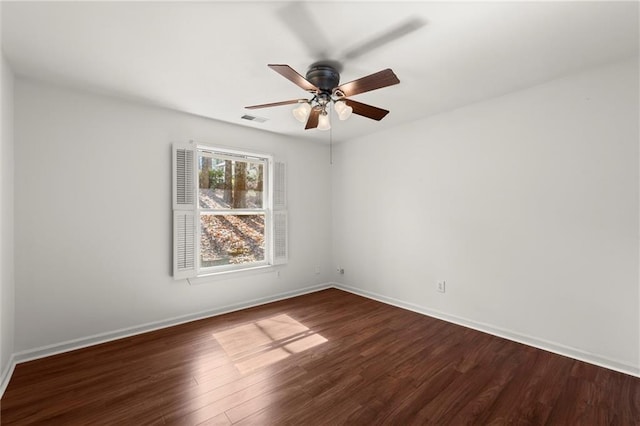 spare room featuring visible vents, baseboards, dark wood finished floors, and a ceiling fan