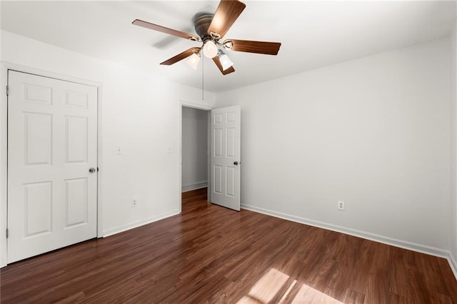 spare room featuring a ceiling fan, dark wood-type flooring, and baseboards