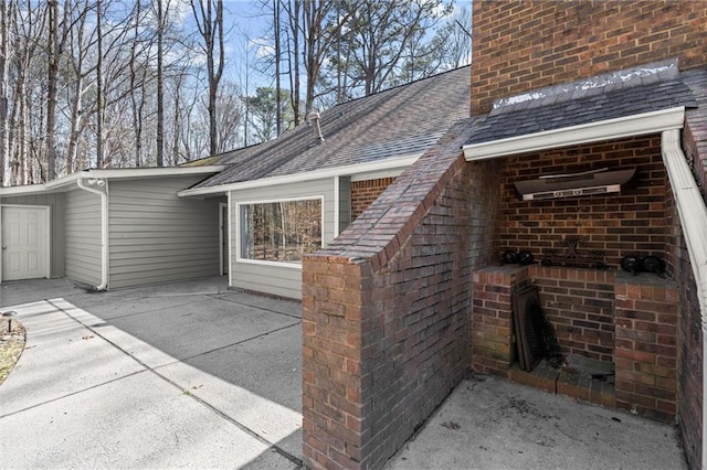 view of property exterior featuring brick siding, a chimney, and roof with shingles