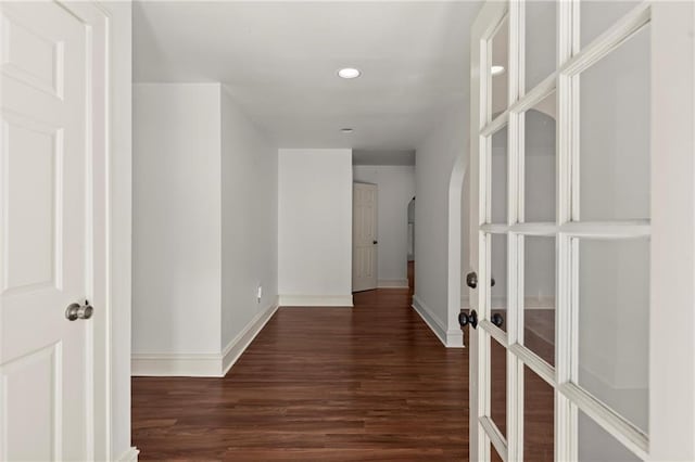 hallway featuring recessed lighting, wood finished floors, arched walkways, and baseboards