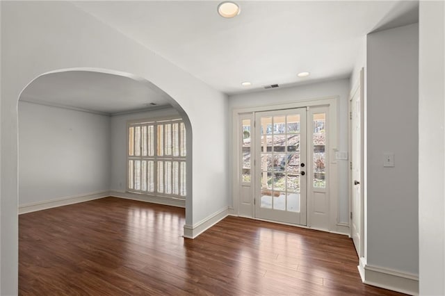 interior space with wood finished floors, visible vents, baseboards, recessed lighting, and arched walkways