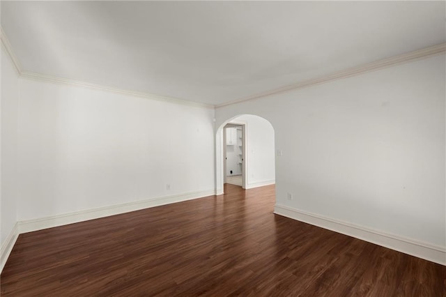 spare room featuring dark wood finished floors, baseboards, arched walkways, and ornamental molding