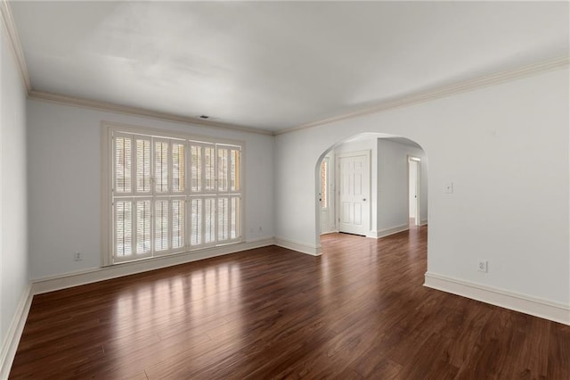 empty room featuring baseboards, arched walkways, wood finished floors, and crown molding