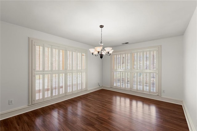 spare room with wood finished floors, visible vents, and a chandelier