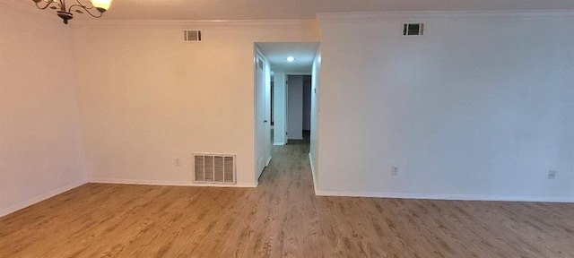 spare room featuring crown molding, a chandelier, and light hardwood / wood-style flooring