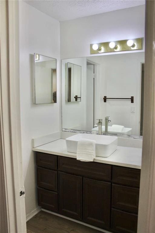 bathroom with vanity, wood-type flooring, and a textured ceiling