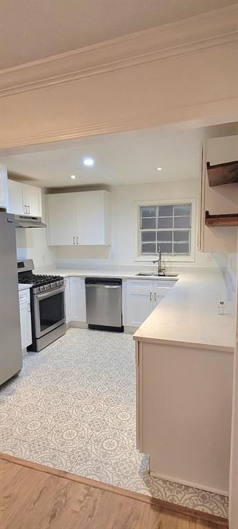 kitchen with sink, crown molding, appliances with stainless steel finishes, light hardwood / wood-style floors, and white cabinets