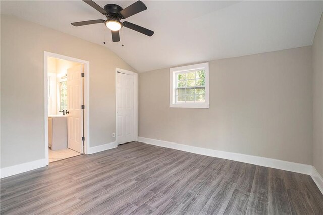 unfurnished bedroom with hardwood / wood-style flooring, a closet, vaulted ceiling, ensuite bathroom, and ceiling fan