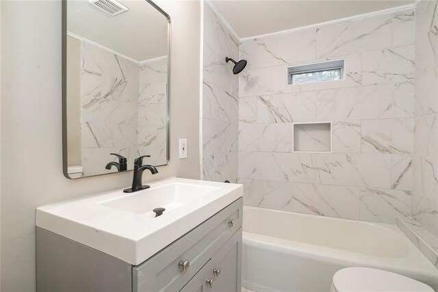 full bathroom with tiled shower / bath, vanity, and toilet