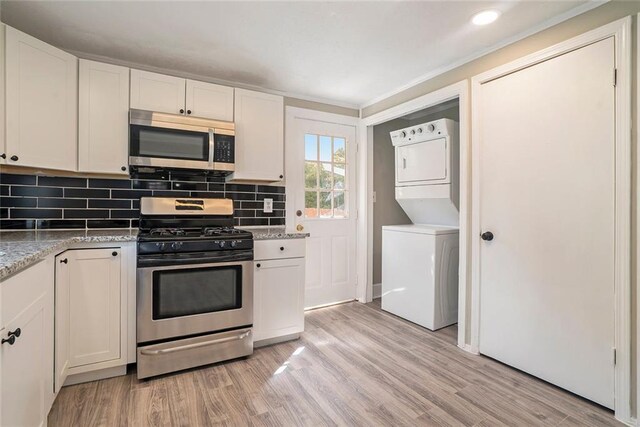 kitchen with white cabinetry, light stone countertops, stacked washer and dryer, light hardwood / wood-style floors, and stainless steel appliances