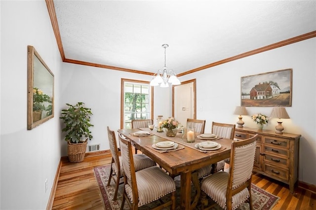 dining area featuring an inviting chandelier, hardwood / wood-style flooring, and ornamental molding