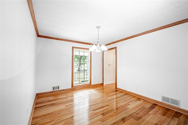 spare room with crown molding, an inviting chandelier, and light hardwood / wood-style flooring