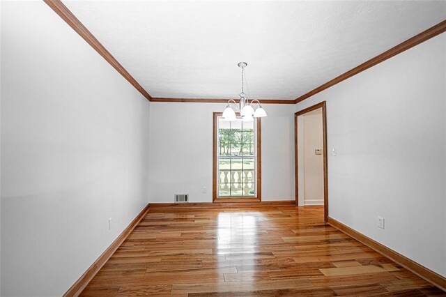 spare room featuring ornamental molding, an inviting chandelier, and light hardwood / wood-style flooring