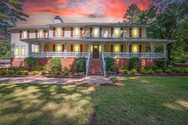 view of front of home with covered porch and a yard