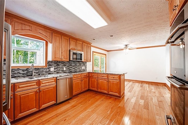 kitchen featuring stainless steel appliances, light hardwood / wood-style floors, ceiling fan, and kitchen peninsula