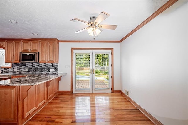 kitchen featuring a textured ceiling, light hardwood / wood-style flooring, backsplash, light stone countertops, and ceiling fan