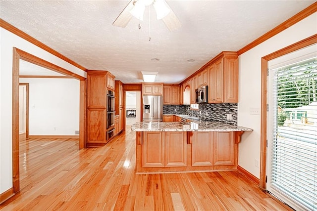 kitchen featuring appliances with stainless steel finishes, kitchen peninsula, light wood-type flooring, ceiling fan, and ornamental molding