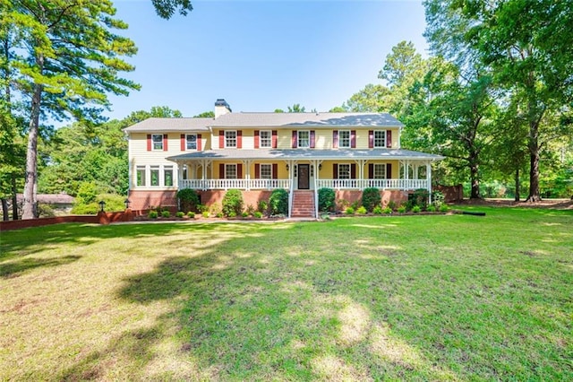 colonial inspired home featuring covered porch and a front yard