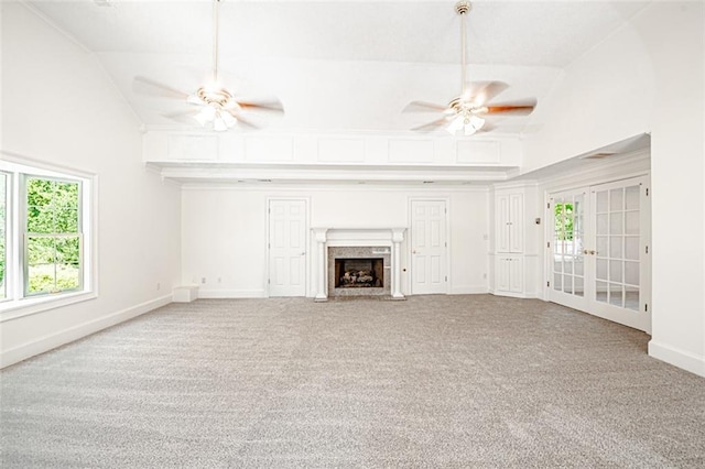 unfurnished living room featuring a high end fireplace, ceiling fan, carpet floors, and french doors