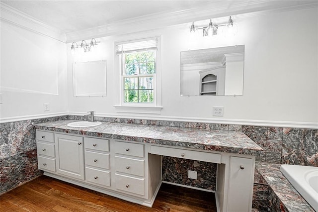 bathroom featuring ornamental molding, wood-type flooring, a tub to relax in, and vanity