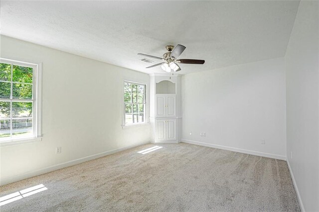 carpeted spare room featuring ceiling fan, a healthy amount of sunlight, and a textured ceiling