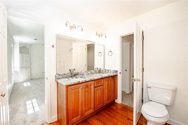 bathroom featuring a textured ceiling, hardwood / wood-style flooring, vanity, and toilet