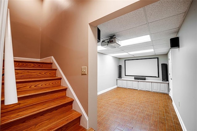 home theater room featuring wood-type flooring and a paneled ceiling