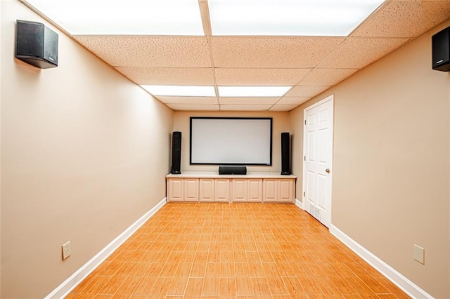 home theater featuring a paneled ceiling and light hardwood / wood-style flooring